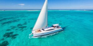 Sailing yacht gliding on turquoise water under sunny skies.