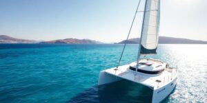 Catamaran sailing Greek islands, clear blue water.