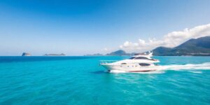 Yacht sailing on turquoise water near green islands.
