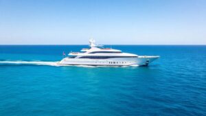 Luxurious white superyacht sailing on a clear blue ocean.