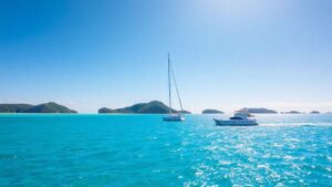 Catamaran sailing on turquoise water near lush islands.