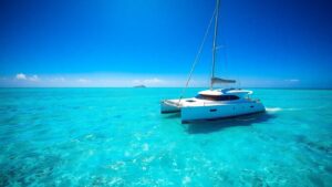 Luxury catamaran sailing on clear turquoise water.