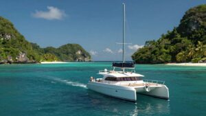Luxury catamaran sailing on turquoise waters near tropical islands.