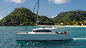 Luxury catamaran sailing on turquoise water near islands.