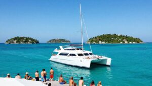 Catamaran sailing on turquoise water near islands.