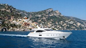 Luxury yacht sailing Amalfi Coast waters with cliffs.