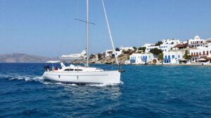 Sailboat on turquoise water near Greek island.