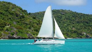 Catamaran sailing on turquoise Caribbean waters near islands.