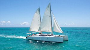 Catamaran sailing on clear blue ocean water.