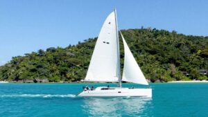 Catamaran sailing on turquoise water near islands.