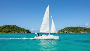 Sailboat on turquoise water near Bahamian islands.