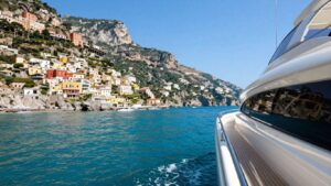Luxury yacht sailing Amalfi Coast waters with cliffside villages.