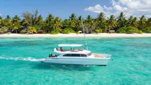 Catamaran sailing in Belize's turquoise waters near islands.