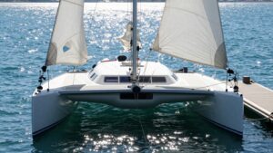 Catamaran sailing into a marina dock.