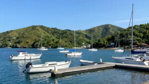 Boats docked in a peaceful harbor with green hills.