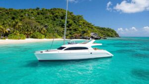 Catamaran sailing on turquoise Caribbean waters near islands.