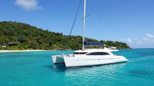 Luxury catamaran sailing on turquoise water near islands.