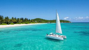 Sailboat on turquoise water near tropical island.