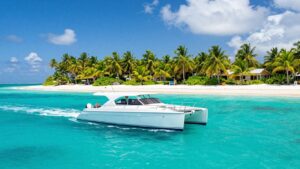 Catamaran sailing in BVI turquoise waters near a beach.